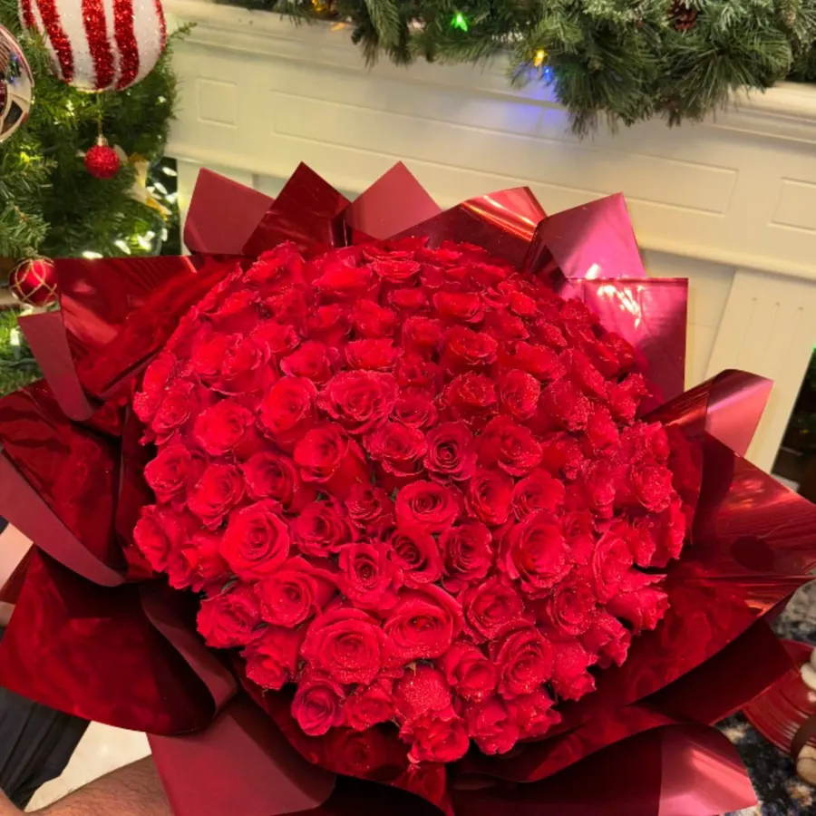 Large bouquet of red roses wrapped in glossy red paper
