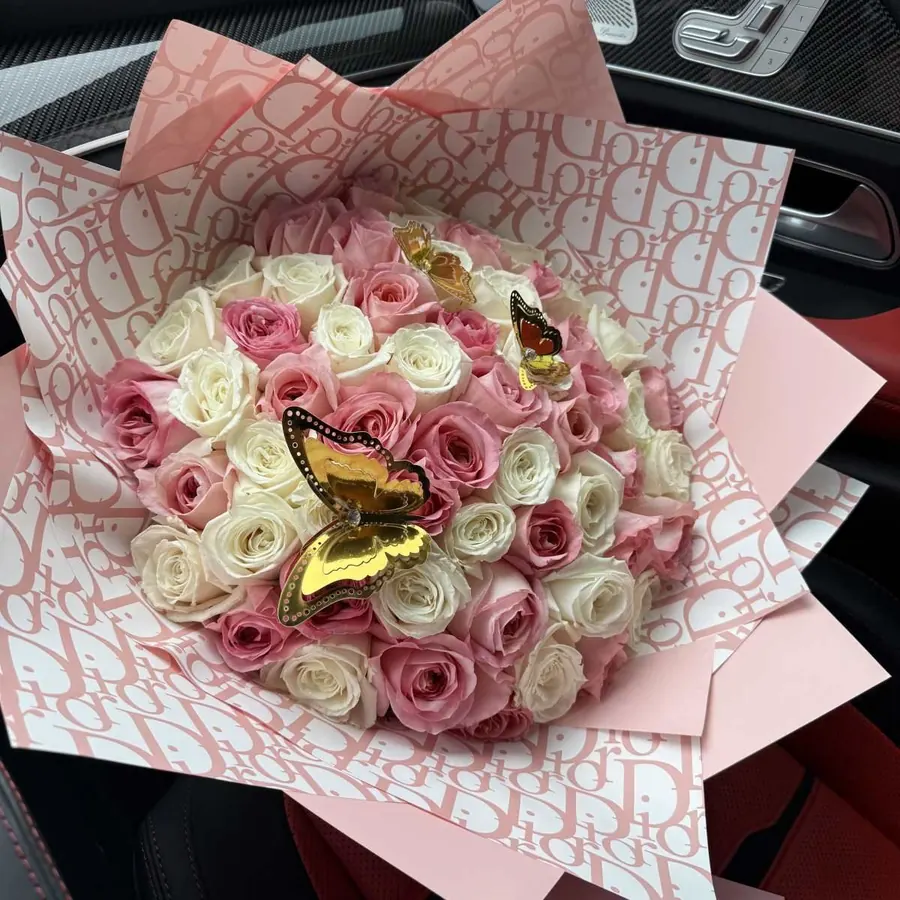 Pink and white rose bouquet wrapped in patterned pink paper with butterfly picks